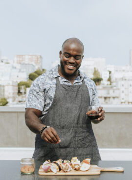 Chef seasoning barbeque skewers at a rooftop party